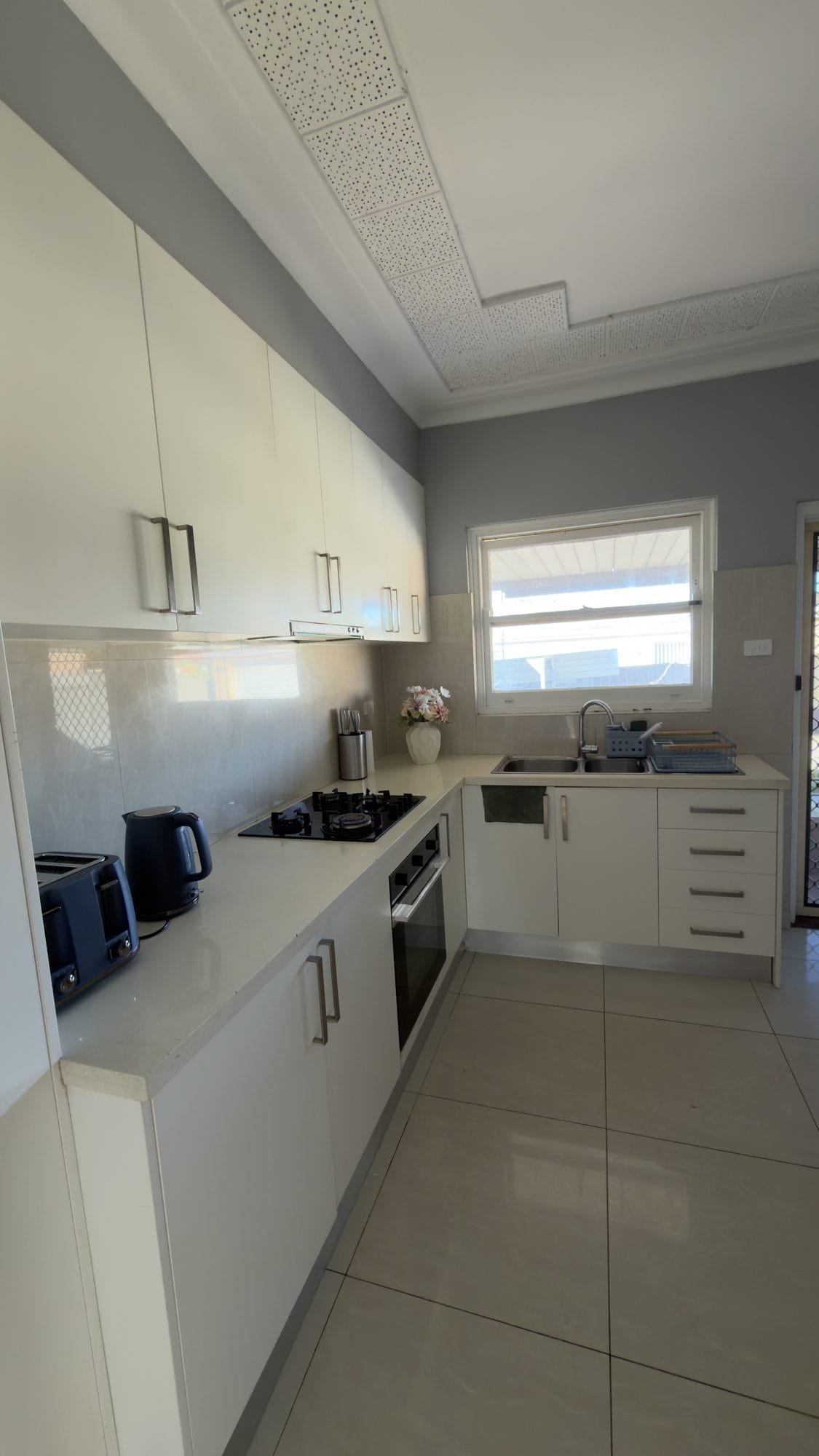 Shared galley kitchen with white cabinets, a gas cooktop, oven and double sink