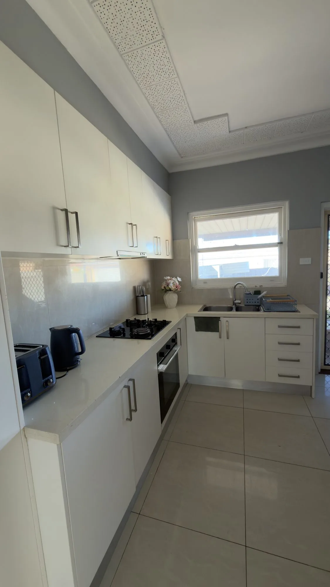 Shared galley kitchen with white cabinets, a gas cooktop, oven and double sink